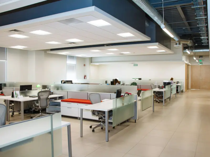 An open-plan office with rows of clear desks and frosted glass partitions